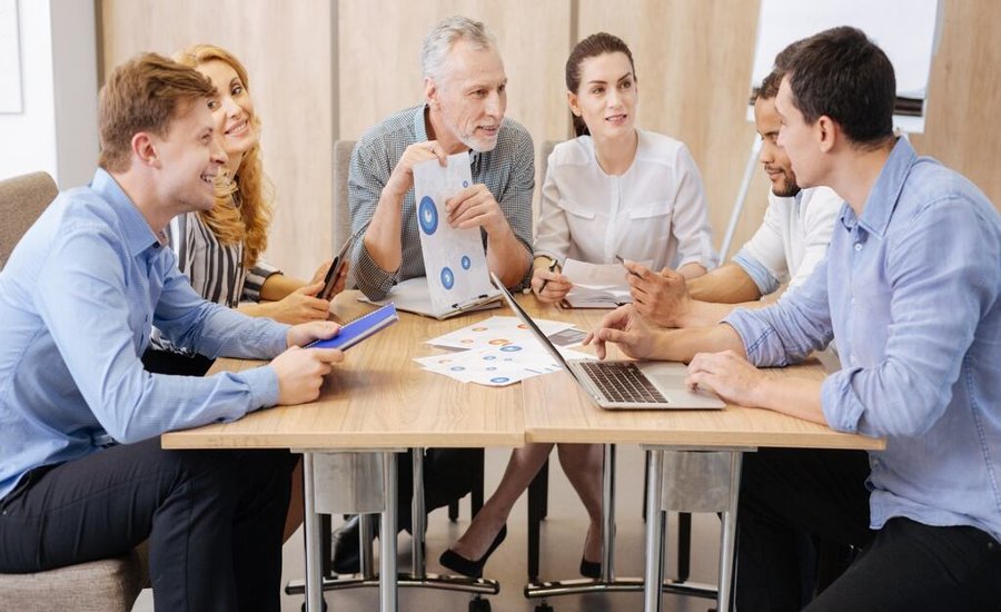 A collaborative team of diverse ages in a modern office, representing a multi-generational workforce engaged in a strategy meeting.